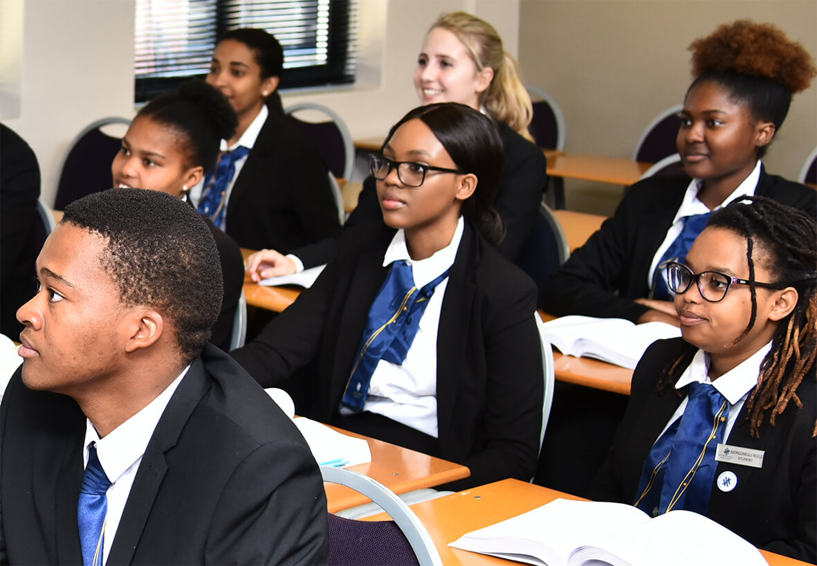Group of students in formal attire attending a classroom session with focused expressions.